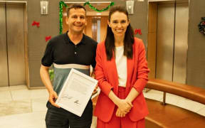 David Seymour and Jacinda Ardern pose after signing a Hansard transcript for charity.