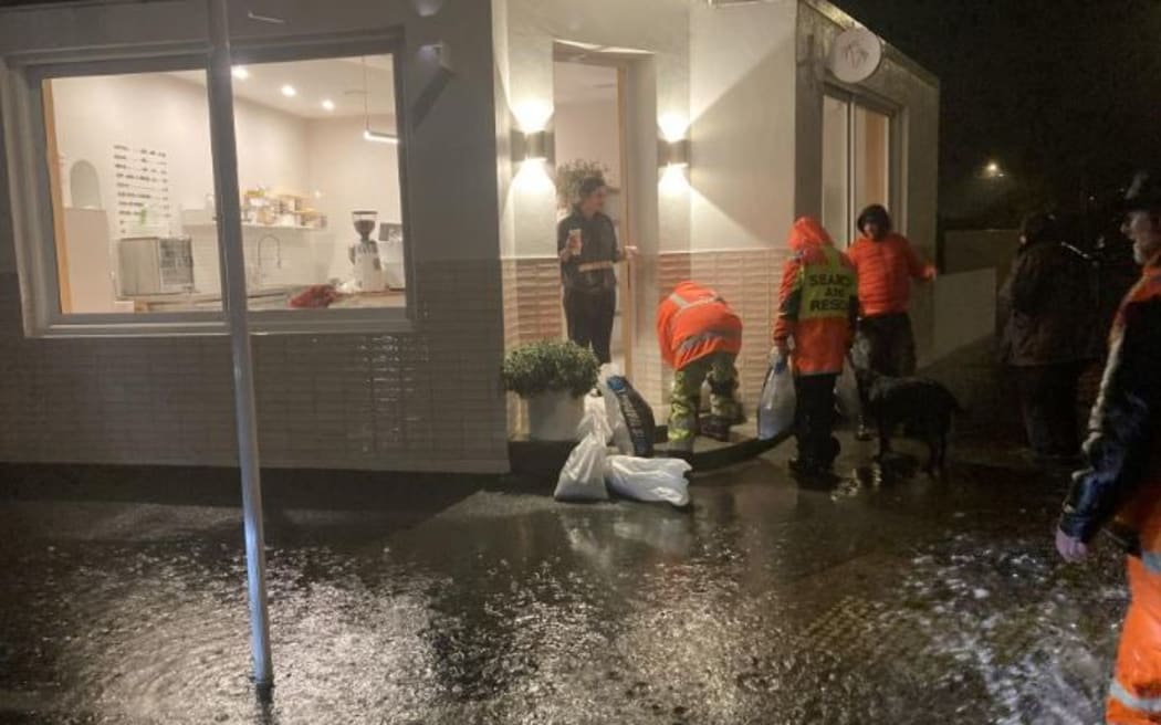 People fill sandbags at the Junction Cafe, on the corner of Hargest Crescent and Richardson Street, in St Clair.