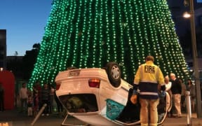 An overturned car under a Christmas tree in central Hamilton.