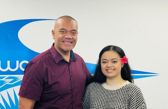 Efeso and Hana stand side by side, smiling at the camera.