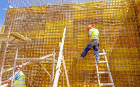 Construction worker is binding rebar for tall reinforced concrete construction.