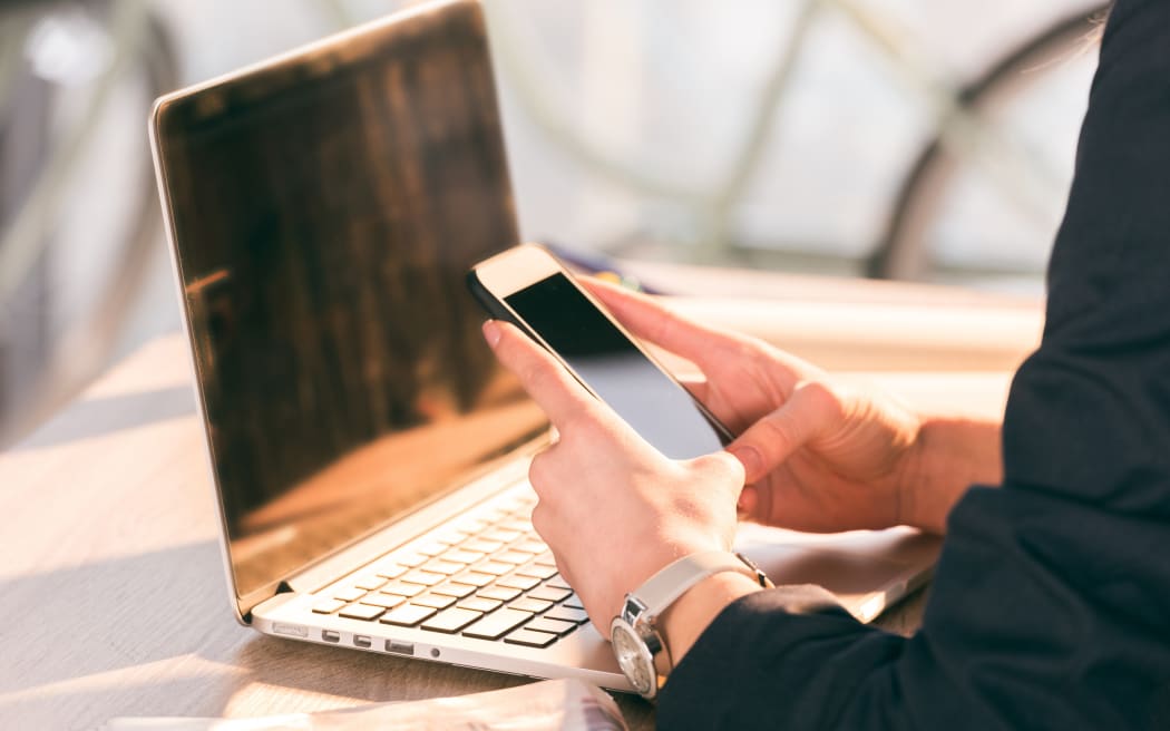 Close-up partial view of businesswoman using laptop and smartphone with blank screens