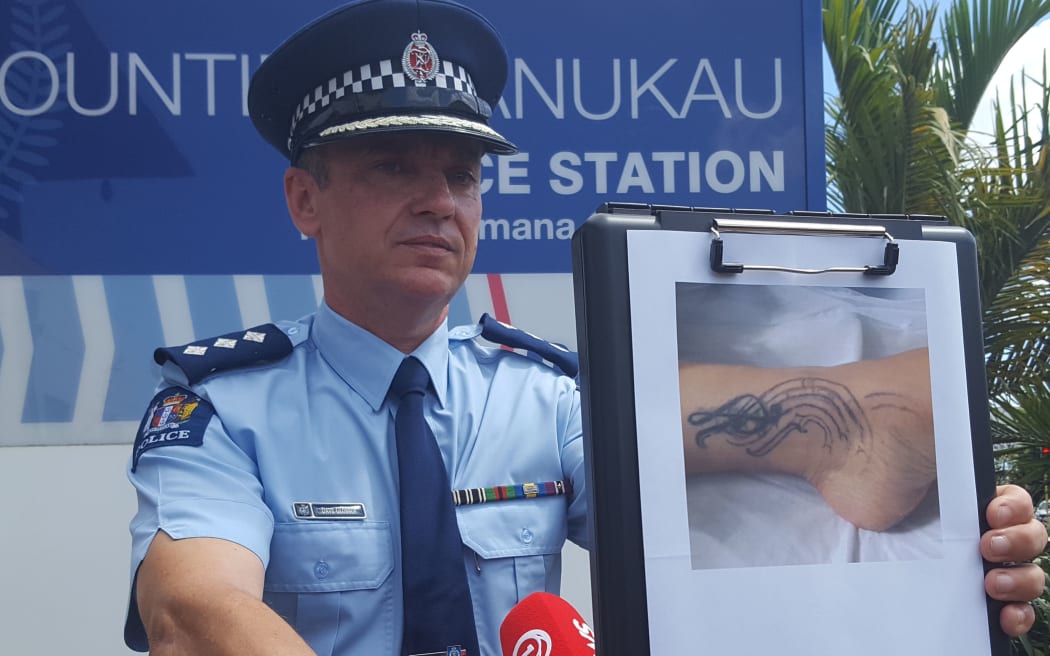 Inspector Dave Glossop holds a picture of the critically injured woman's tattoo.