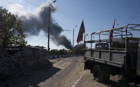 A pro-Russian separatist checkpoint in Donetsk as smoke rises from the airport area in the background.