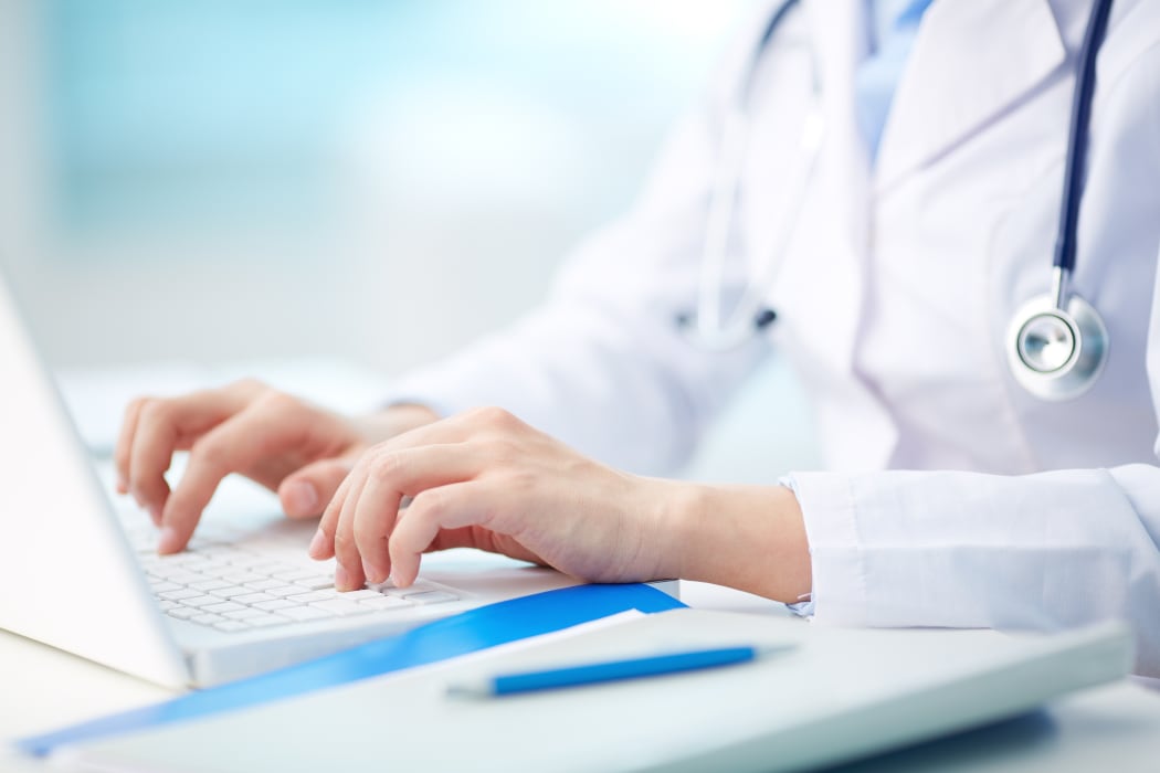 An image of a doctor typing on a laptop