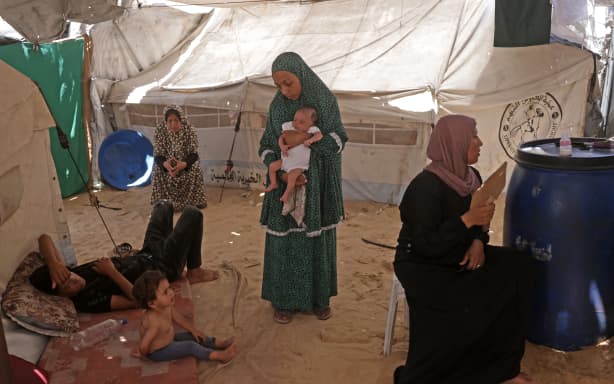 A displaced Palestinian girl (L), who according to doctors is suffering from chickenpox, sits inside the family’s tent in Khan Yunis, in the southern Gaza Strip, on July 19, 2026. Doctors and displaced families in Gaza say the highly contagious disease has surged in recent months as war has forced hundreds of thousands of Palestinians into cramped tent camps with no clean water for hygiene. UNICEF said health officials had already recorded more than 9,300 suspected cases of chickenpox across Gaza in early July, concentrated mainly in Khan Yunis in the south. (Photo by Bashar Taleb / AFP)