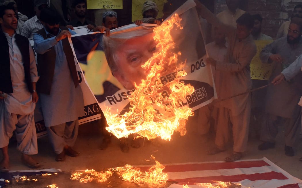 Pakistani protesters burn a US flag and a banner bearing an image of the US President Donald Trump in April 2018