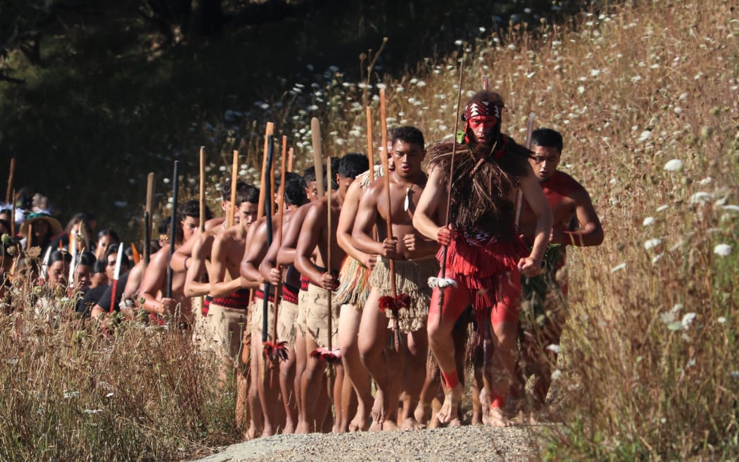 Warriors from mass haka group Te Tira Taua advance on a waiting crowd during 175th anniversary commemorations of the Battle of Ruapekapeka Pā in 2021.