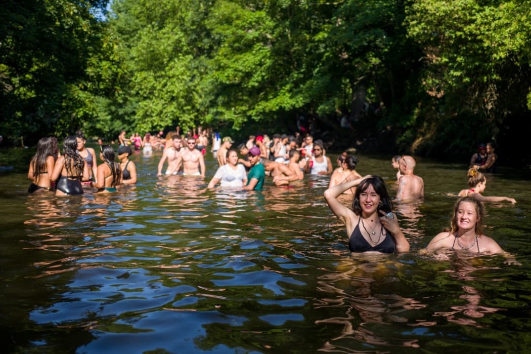 Sun-seekers cool off in the water and sunbathe on the riverbank at Hackney Marshes in east London on June 24, 2020, as temperatures reached 31 degrees.