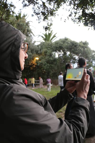 A Muslim woman compares a chart on her phone with the horizon to find the location of the moon during sunset at Point Chevalier's Coyle Park on 18 February, 2026.