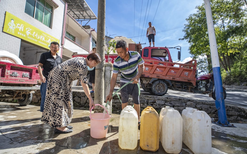 A villager gets water at a water distribution point in Luoping Village of Wushan County, southwest China's Chongqing, 13 August, 2022.