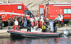 Divers of the Vigili del Fuoco, the Italian Corps. of Firefighters, are pictured on a small boat in Porticello near Palermo, on August 20, 2024 a day after the British-flagged luxury yacht Bayesian sank. Specialist divers launched a fresh search for six people, including UK tech tycoon Mike Lynch and the chairman of Morgan Stanley International, missing since their yacht capsized off the Italian island of Sicily. The Bayesian, which had 22 people aboard including 10 crew, was anchored some 700 metres from port before dawn when it was struck by a waterspout, a sort of mini tornado. Fifteen people aboard, including a mother with a one-year-old baby, were plucked to safety; one man has been found dead; and six people remain missing. (Photo by Alberto PIZZOLI / AFP)