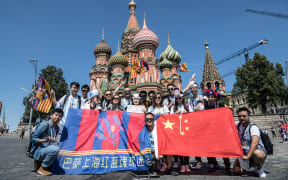 Chinese football fans of Lionel Messi, Argentina, holding flags of FC Barcelona and China, pose for photos in front of Saint Basil's Cathedral as they visit the city during the 2018 FIFA World Cup in Moscow, Russia, 17 June.