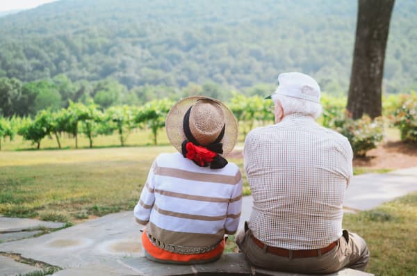 An elderly couple sitting outdoors in nature.