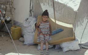 A young Palestinian girl looks into the camera as displaced Palestinians live in temporary tents set up near demolished buildings as displacement crisis worsens in Gaza, Palestinian territories on May 29, 2025. (Photo by Abood Abusalama / Middle East Images / Middle East Images via AFP)