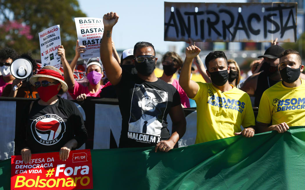 People raise their fists during a protest against Brazilian President Jair Bolsonaro and racism in Brasilia, Brazil, on June 21, 2020, amid the COVID-19 coronavirus pandemic.