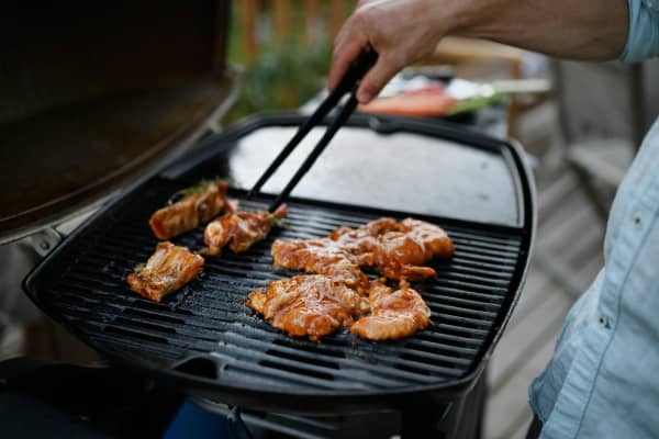 Chicken pieces on a grill outdoors.