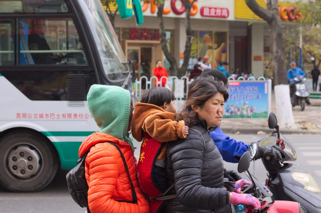 A family negotiates traffic on a scooter in Kunming, China.