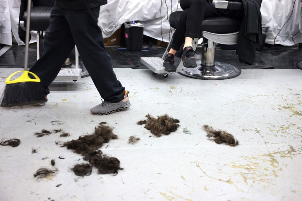Hair is swept in a barber shop on Induction Day at the U.S. Naval Academy on June 30, 2021 in Annapolis, Maryland.