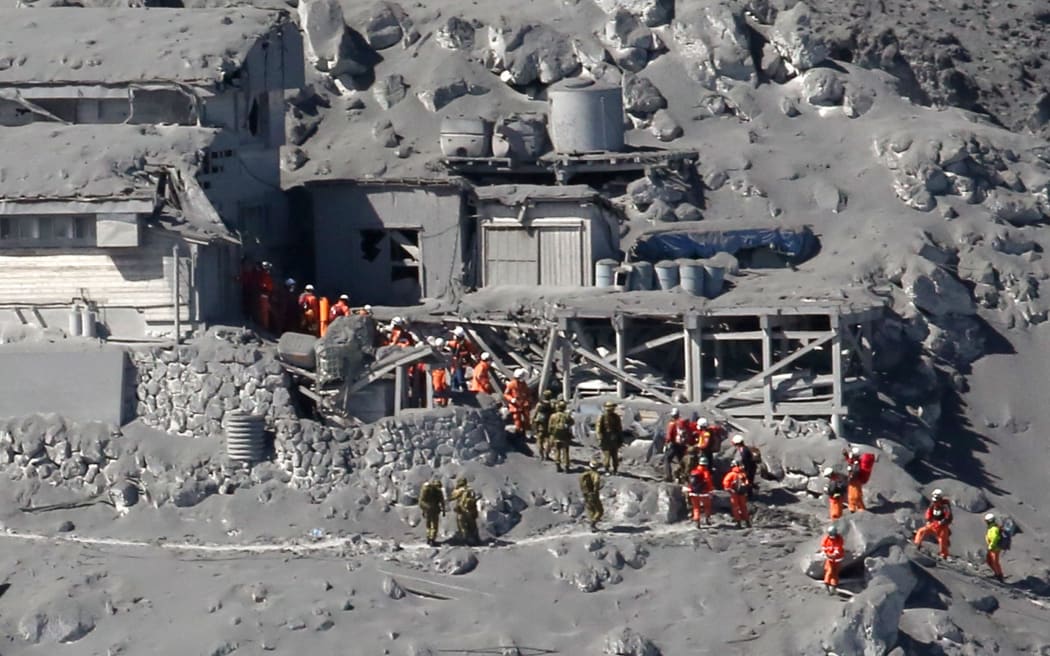 Rescue workers and soldiers searching for missing climbers and survivors in ash-covered cottages on Mount Ontake.