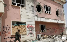 A fighter from a Shiite paramilitary units, known as Hashd Shaabi, walks near a damaged building in Harariyat village on the outskirts of Fallujah.