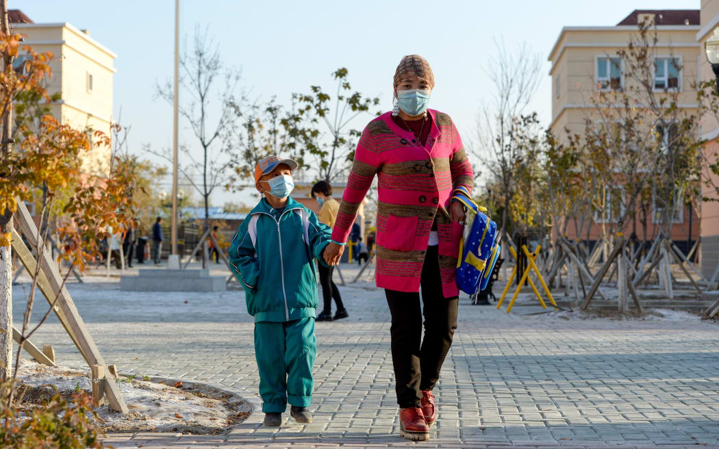 A woman and her child are on the way to their new house in Axili Town of Changji, northwest China's Xinjiang Uygur Autonomous Region, Oct. 16, 2020.