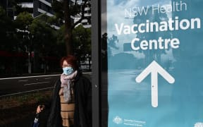 A woman walks past the vaccination centre signage in Sydney on June 29, 2021, as about 10 million Australians have been ordered into lockdown as Covid-19 spreads across the country