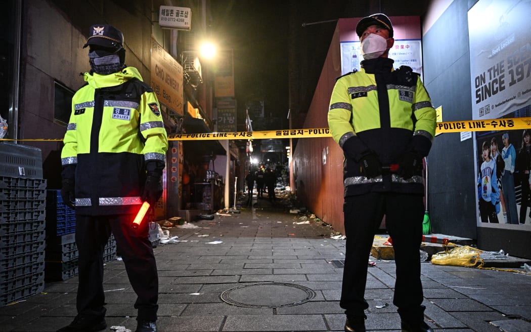 EDITORS NOTE: Graphic content / Police stand guard to restrict access to the alley where a Halloween stampede took place in the neighbourhood of Itaewon in Seoul on October 30, 2022. - More than 140 people were killed on October 29 and some 150 were injured in a horrific stampede in central Seoul when a large crowd celebrating Halloween crammed into a narrow street, officials said. (Photo by Anthony WALLACE / AFP)