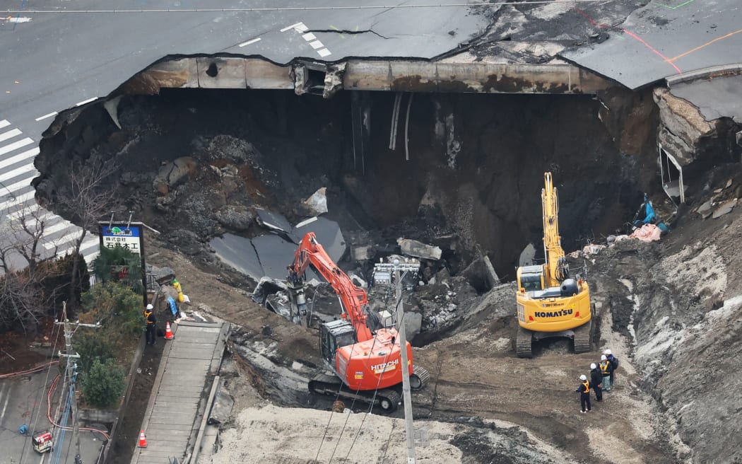 An aerial photo shows the site of a road collapsed above huge sinkholes at an intersection in Yashio City, Saitama Prefecture, adjacent to Tokyo on February 2, 2025. The hole appeared on Jan. 28th, and swallowed a truck and a driver. The search effort for the 74-year-old man remains suspended after a quantity of water was found in the hole. The cause of the road collapse is believed to be the breakage of an old sewer pipe.   ( The Yomiuri Shimbun ) (Photo by Daisuke Urakami / Yomiuri / The Yomiuri Shimbun via AFP)