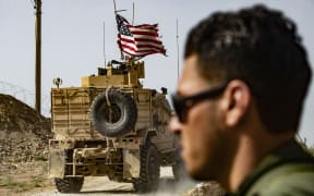 A US soldier sits atop an armoured vehicle during a demonstration by Syrian Kurds against Turkish threats next to a base for the US-led international coalition on the outskirts of Ras al-Ain town in Syria's Hasakeh province near the Turkish border on 6 October 2019.