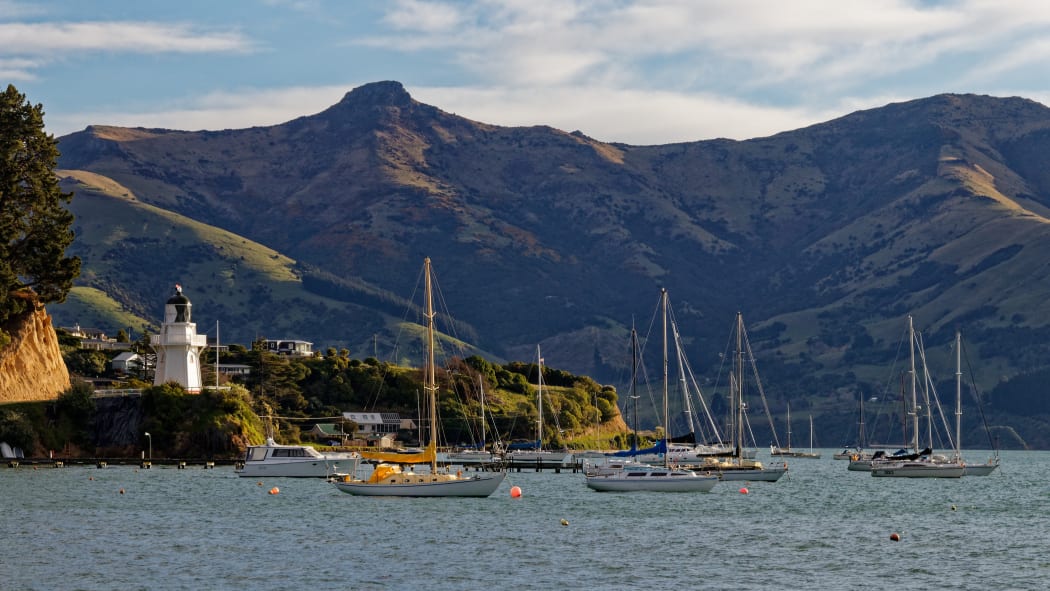 Akaroa lighthouse and harbour with moored yachts, Banks Peninsula, New zealand.