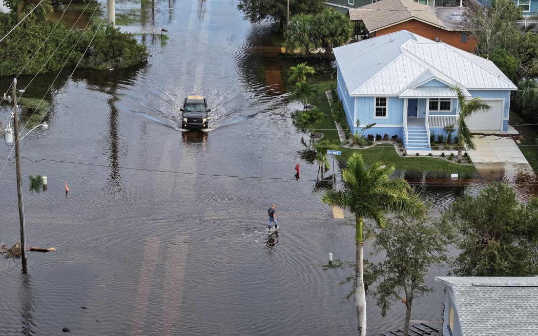 PUNTA GORDA - OCTOBER 10: In this aerial view, a person walks through flood waters that inundated a neighborhood after Hurricane Milton came ashore on October 10, 2024, in Punta Gorda, Florida. The storm made landfall as a Category 3 hurricane in the Siesta Key area of Florida, causing damage and flooding throughout Central Florida.   Joe Raedle/Getty Images/AFP (Photo by JOE RAEDLE / GETTY IMAGES NORTH AMERICA / Getty Images via AFP)
