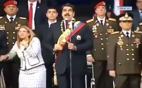 Venezuelan President Nicolas Maduro (C), his wife Cilia Flores (L) and military authorities reacting to a loud bang during a military ceremony.