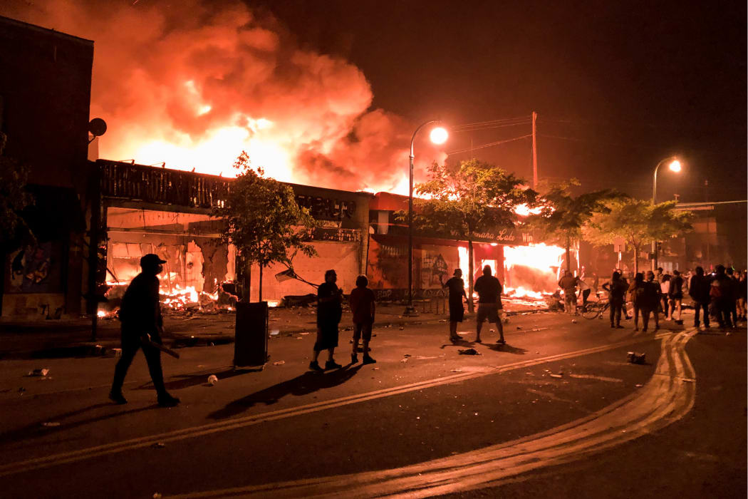 Flames rise from a liquor store and shops near a police station set on fire during a third night of protests in Minneapolis.