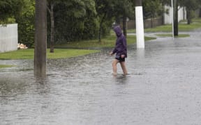 A Christchurch resident wades through a flooded street.