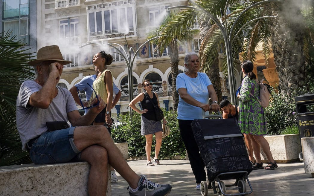 People take advantage of water mist fountains in Valencia, Spain on June 21, 2025, as parts of the country experience a heatwave.