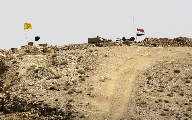 A picture taken in August during a tour guided by the Lebanese Shiite Hezbollah movement shows the flags of the movement and the Syrian government (R) flying over a position held by the Syrian government forces near the border with Lebanon.