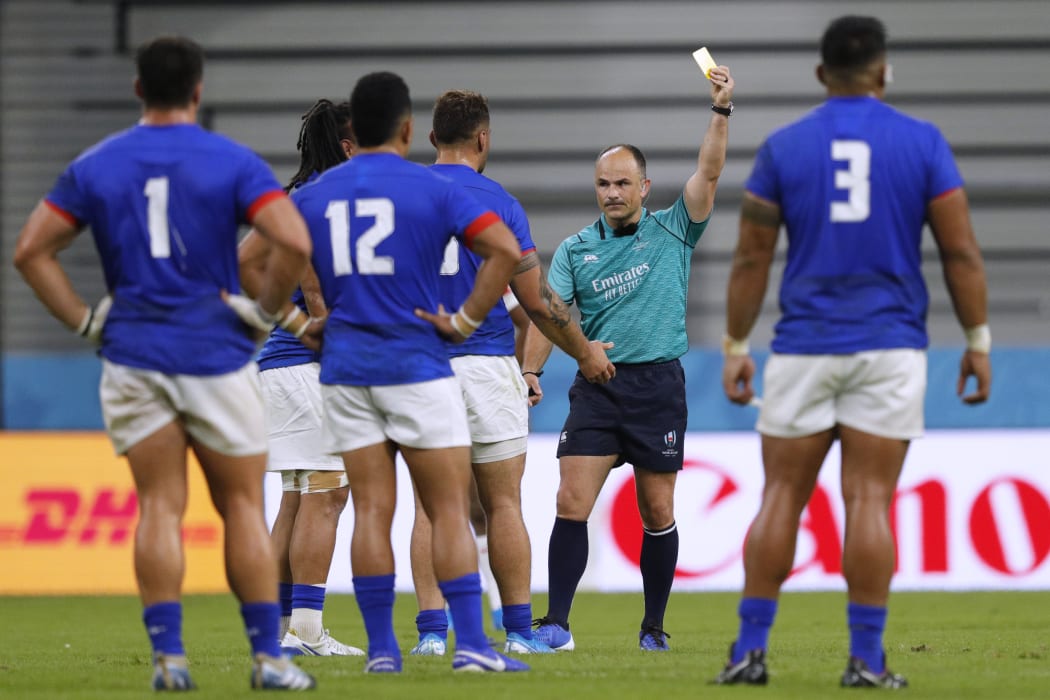 South African referee Jaco Peyer shows TJ Ioane (obscured) a yellow card.