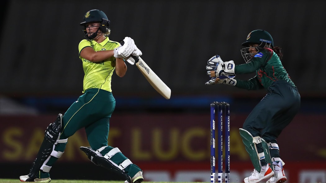Dane van Niekerk of South Africa hits the ball towards the boundary, as Nigar Sultana of Bangladesh looks on during the ICC Women's World T20 2018 match.