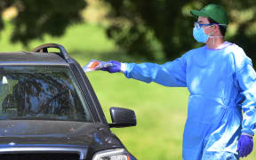A healthcare volunteer wearing protective gear gives a Covid-19 test kit to a driver at a mobile test site in Los Angeles, California on 23 April 2020.