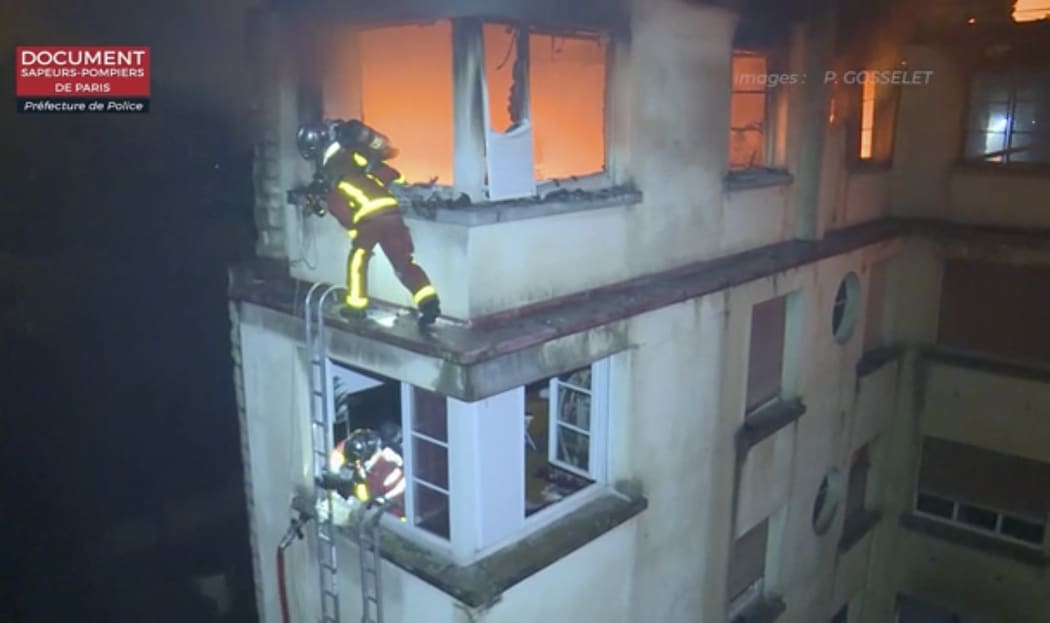 Firefighters scale the top floors of an apartment building on fire in Paris, France.