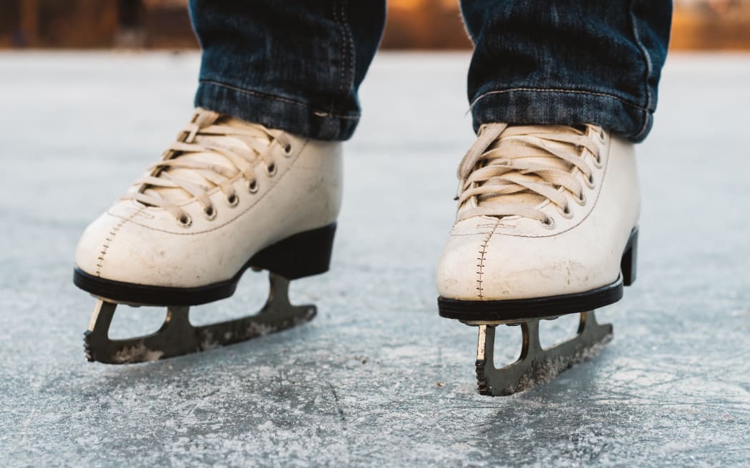 A young girl standing in skates on a frozen pond on ice. Beautiful winter day, nice blurred background.