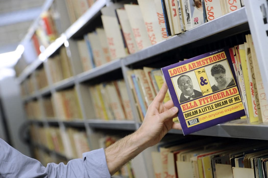 A vynil LP of US jazz musician Louis Armstrong and singer Ella Fitzgerald is taken from a rack on October 19, 2011 in Paris at the music library of the public media group Radio France.  AFP PHOTO MIGUEL MEDINA (Photo by MIGUEL MEDINA / AFP)