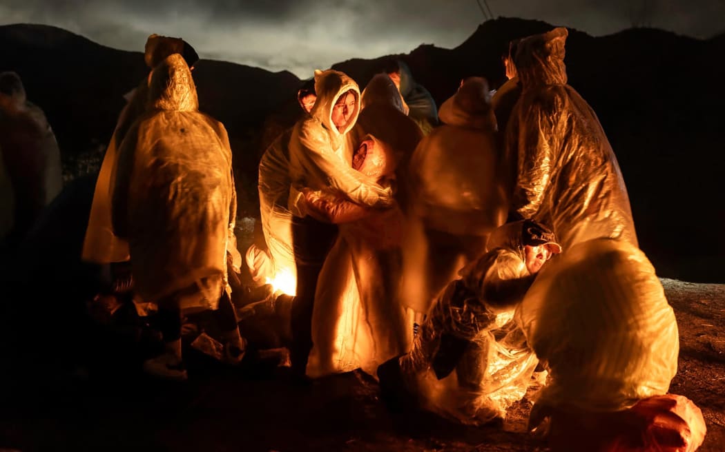 Chinese migrants warm themselves under a cold rain after crossing the US-Mexico border, in Campo, California.