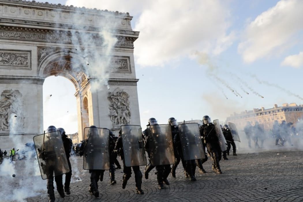 Riot police charge using tear gas canister at the Arc de Triomphe on the Place de l'Etoile in Paris