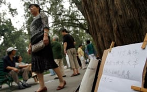 A Chinese parent walks past a board displaying a notice for a "to be married" 38 years old woman.