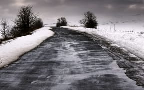 Black asphalt road in the field in the winter. Dark winter day