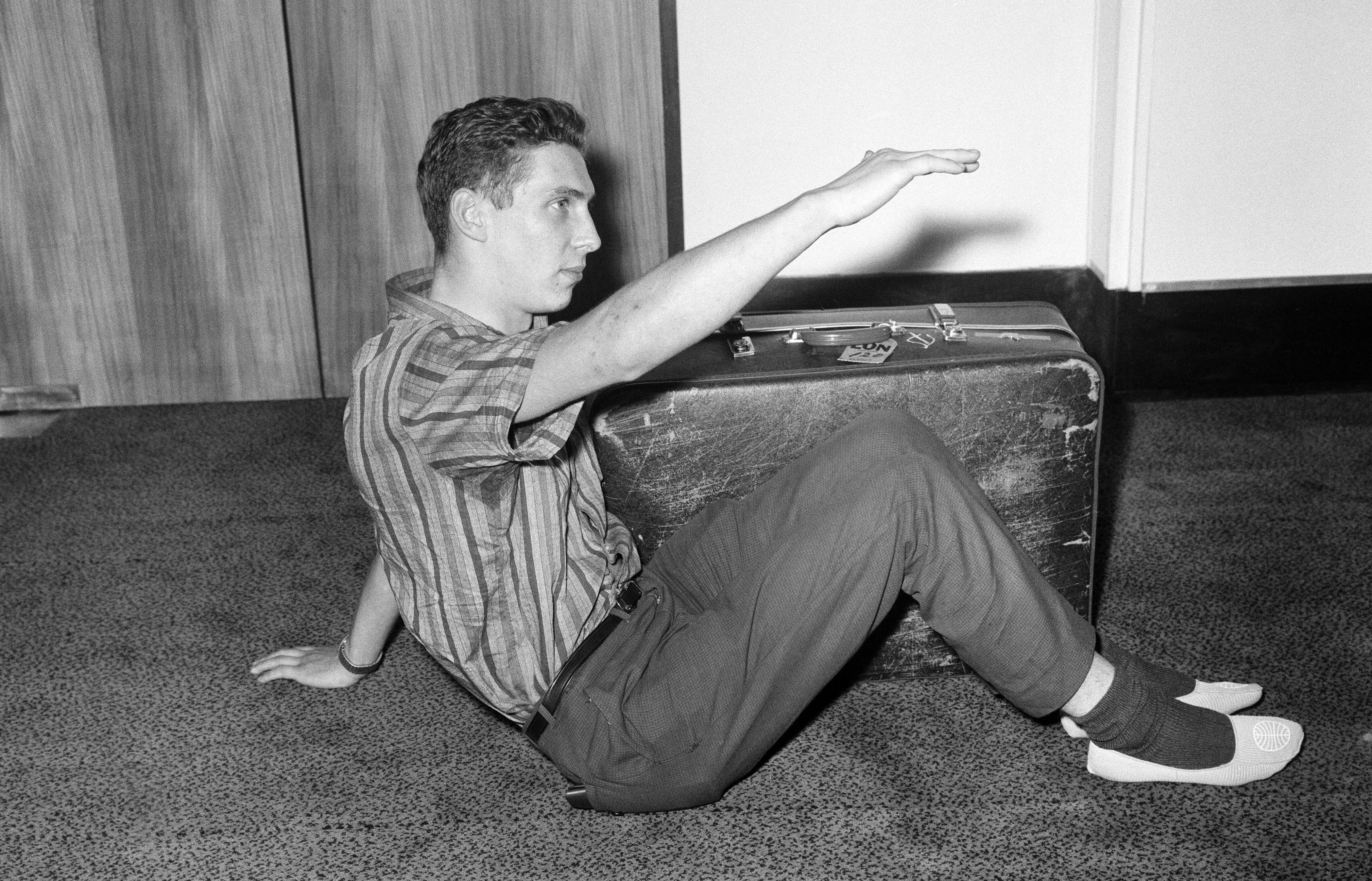 Brian Robson tried to mail himself from Australia to London in 1965. Brian shows how he sat with his suitcase in the packing case.