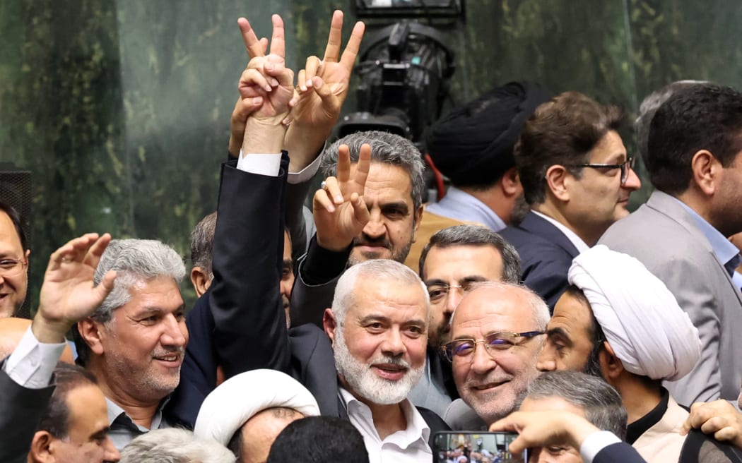 Ismael Haniyeh, Palestinian leader of the militant group Hamas, surrounded by lawmakers flashes the victory sign during the swearing in ceremony for the new Iranian President, at the parliament in Tehran on July 30, 2024.