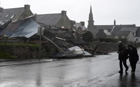 Pedestrians walk past a destroyed warehouse in Porspoder, western France, on November 2, 2023, as the storm Ciaran hits the region. Much of northwestern Europe went on high alert on November 1, 2023 as a storm dubbed Ciaran threatened to bring gale-force winds and extreme rainfall to the region.